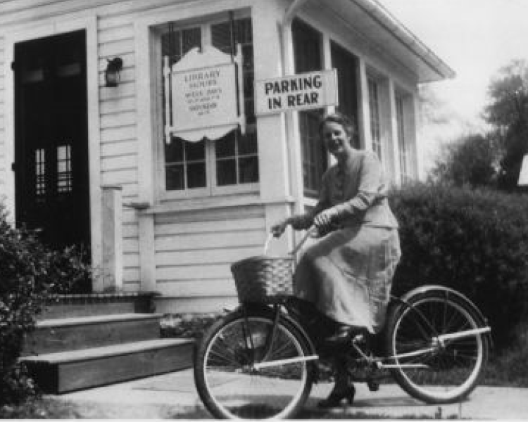 woman on bike in front of library in 1950 